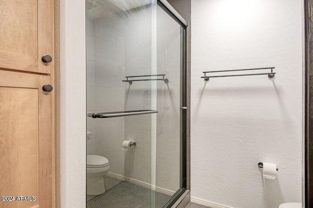 bathroom with tile patterned flooring, toilet, and a shower with shower door