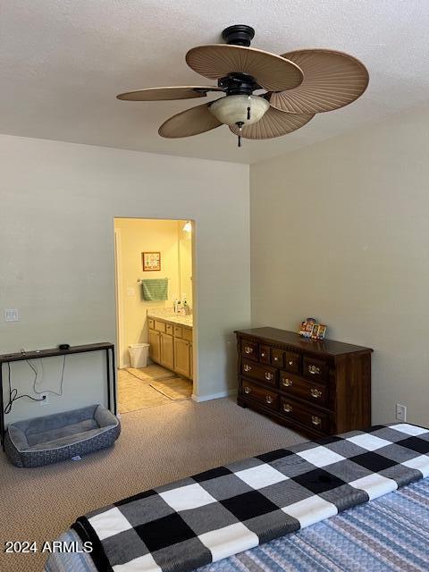 carpeted bedroom featuring ensuite bath, a textured ceiling, and ceiling fan