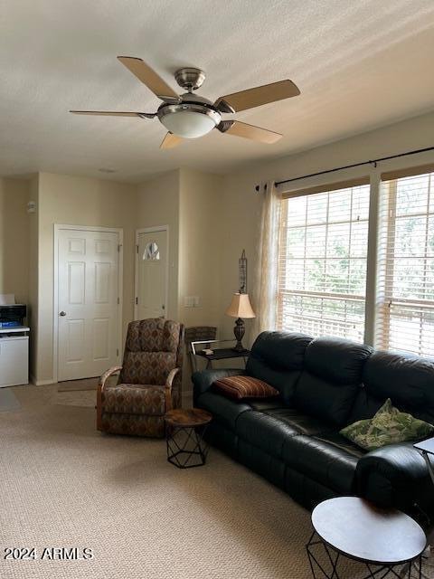 carpeted living room with a textured ceiling and ceiling fan