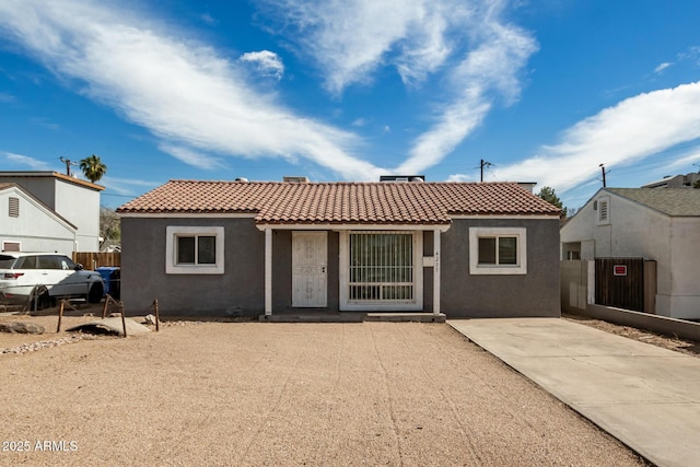 back of house with a tile roof and stucco siding