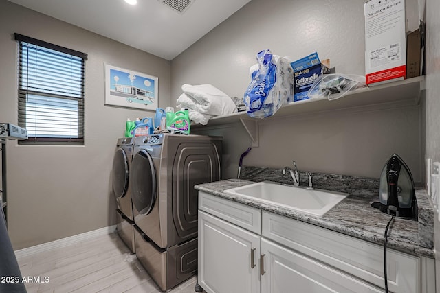 laundry area featuring cabinets, sink, washing machine and clothes dryer, and light wood-type flooring