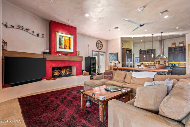 tiled living room with a high end fireplace and ceiling fan