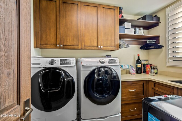 clothes washing area featuring independent washer and dryer, cabinets, and sink