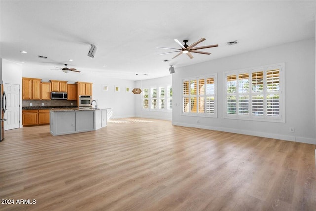 unfurnished living room featuring ceiling fan and light hardwood / wood-style flooring