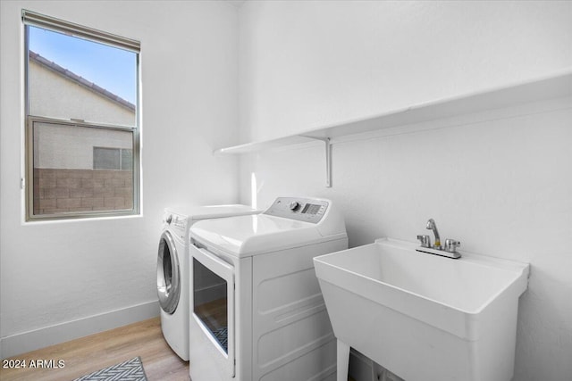 laundry room featuring independent washer and dryer, light wood-type flooring, and sink