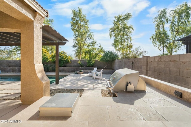 view of patio featuring a fenced in pool, a grill, and an outdoor kitchen