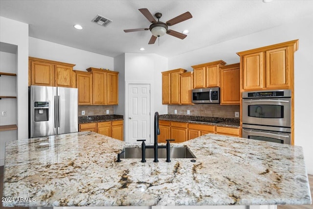 kitchen with sink, ceiling fan, tasteful backsplash, light stone counters, and stainless steel appliances