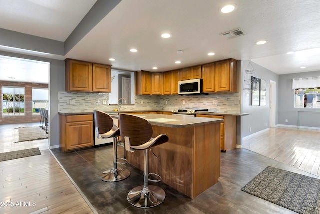 4304 W Calle Poco, Laveen, AZ 85339 - kitchen with white microwave, electric stove, baseboards, a center island, and brown cabinetry