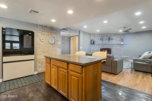 4304 W Calle Poco, Laveen, AZ 85339 - kitchen featuring a brick fireplace, a center island, a ceiling fan, baseboards, and open floor plan