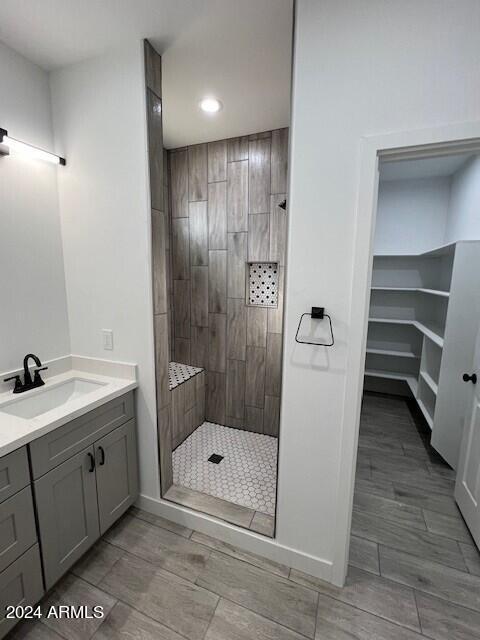 bathroom featuring a tile shower, vanity, and tile patterned floors