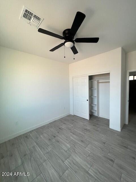 unfurnished bedroom with ceiling fan, a closet, and wood-type flooring