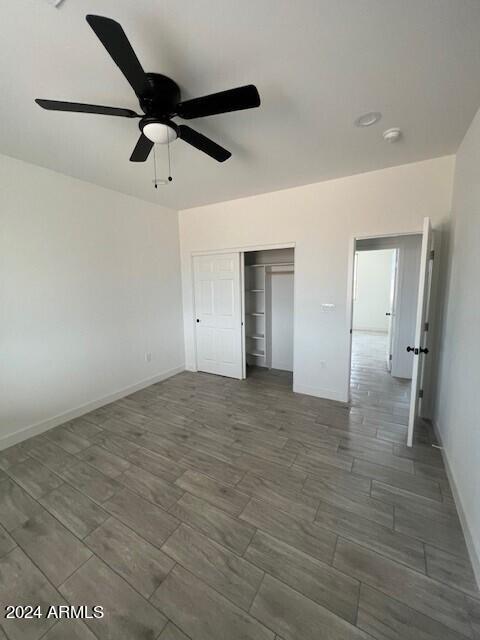 unfurnished bedroom with ceiling fan and a closet