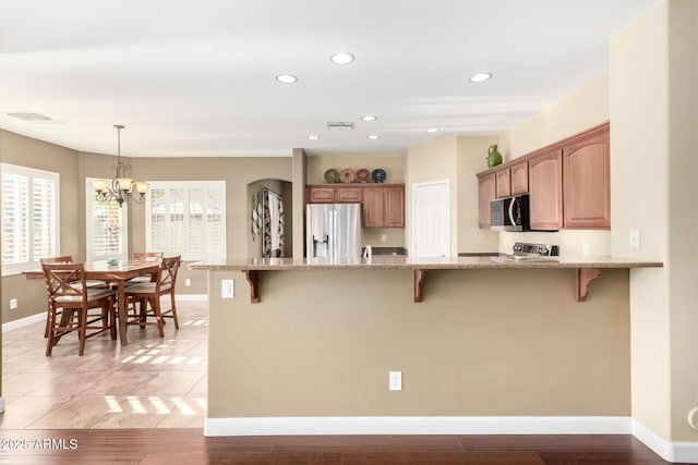 kitchen featuring appliances with stainless steel finishes, a breakfast bar, light stone counters, and visible vents