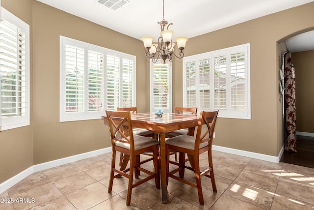 dining space with visible vents, arched walkways, a chandelier, and a wealth of natural light