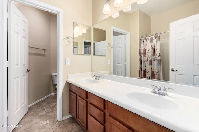 full bath featuring double vanity, a sink, baseboards, and toilet