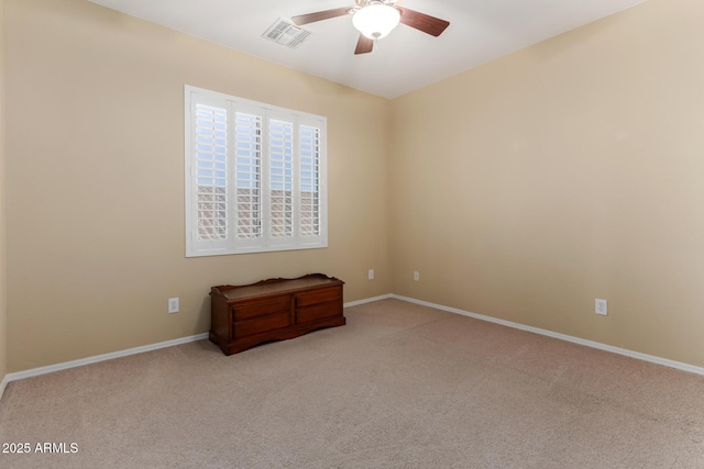 carpeted spare room with visible vents, baseboards, and ceiling fan
