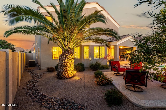 back of property with a fenced backyard, central AC unit, stucco siding, and a patio area