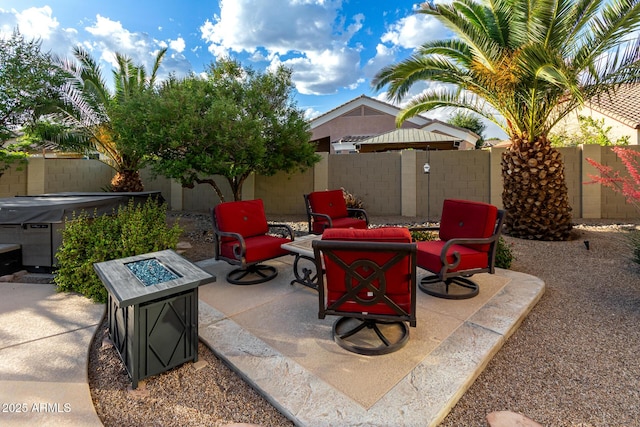 view of patio with a hot tub, a fenced backyard, and an outdoor fire pit