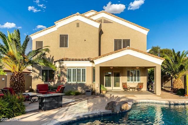 rear view of house featuring stucco siding, a fire pit, a tiled roof, and a patio area
