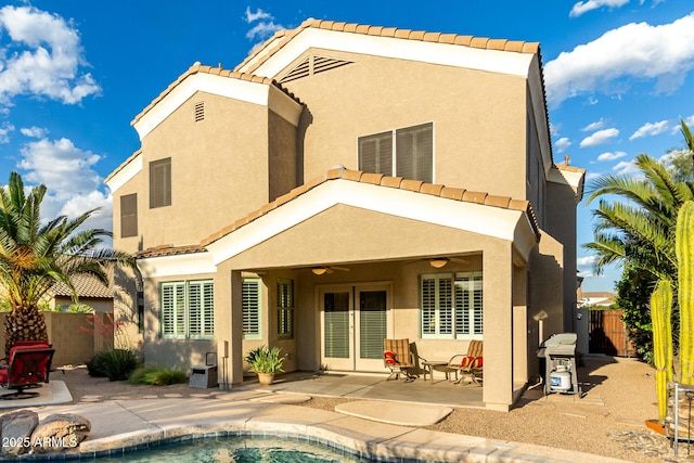 back of property with a ceiling fan, stucco siding, a tile roof, and fence