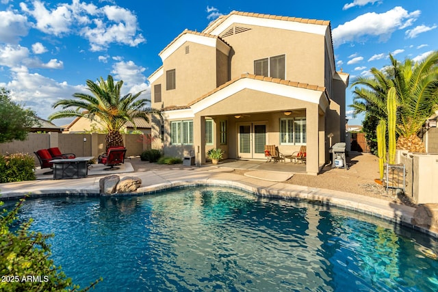 rear view of property with ceiling fan, a fire pit, a patio, stucco siding, and a tile roof
