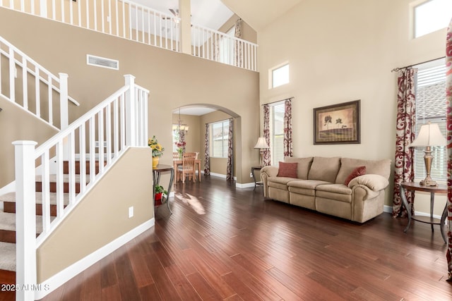 living room with visible vents, stairs, a towering ceiling, baseboards, and arched walkways