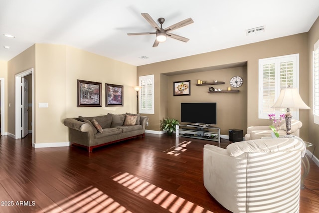 living area featuring visible vents, a ceiling fan, baseboards, and wood finished floors