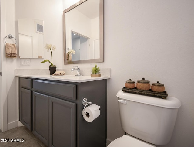 bathroom with toilet, vanity, and tile patterned flooring