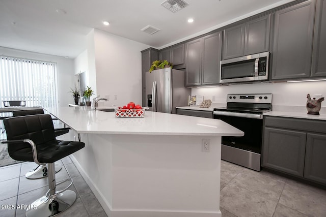 kitchen featuring light tile patterned floors, a kitchen island with sink, appliances with stainless steel finishes, and sink