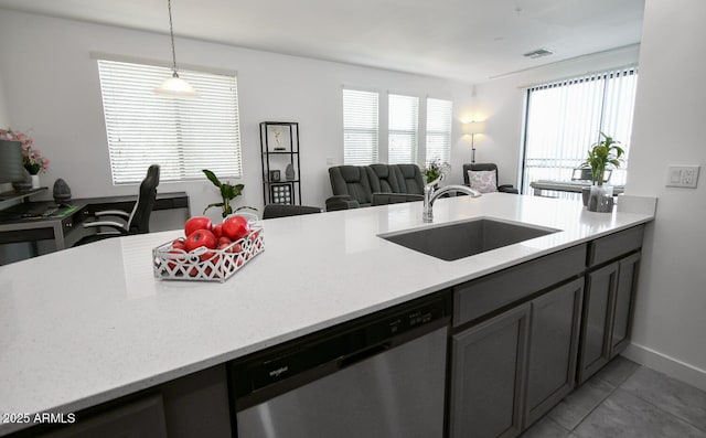 kitchen featuring dishwasher, sink, hanging light fixtures, light stone counters, and light tile patterned floors