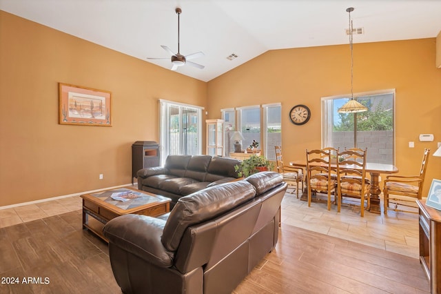 living room featuring lofted ceiling, light wood finished floors, visible vents, and a ceiling fan