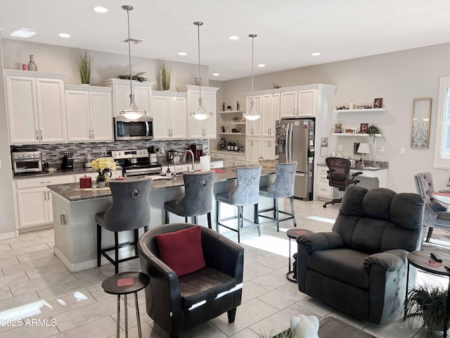 kitchen with a kitchen island with sink, pendant lighting, a kitchen breakfast bar, and appliances with stainless steel finishes