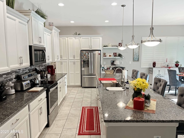 kitchen with a large island, sink, decorative light fixtures, and stainless steel appliances