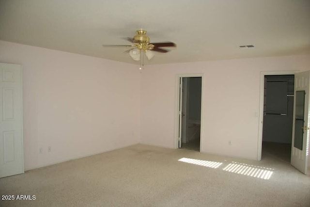 unfurnished bedroom featuring a spacious closet, visible vents, light carpet, a closet, and a ceiling fan