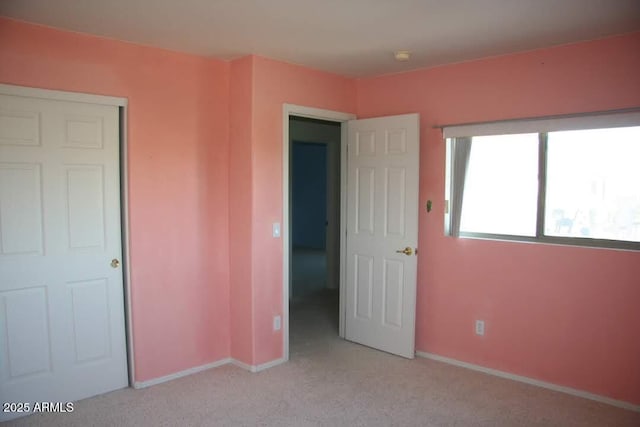 unfurnished bedroom featuring baseboards and light carpet