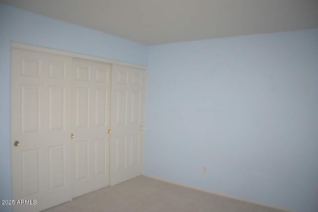 unfurnished bedroom with a closet and light carpet