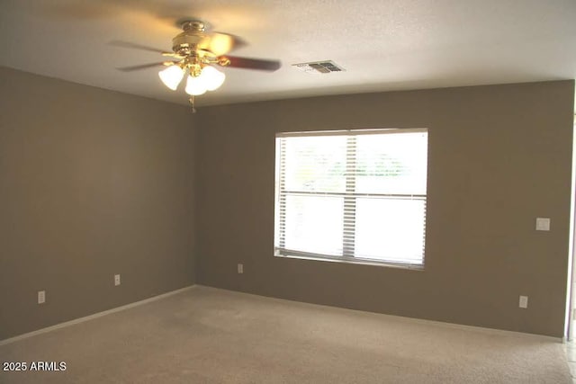 unfurnished room with visible vents, light colored carpet, and ceiling fan