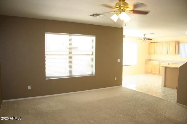 unfurnished living room featuring visible vents, light tile patterned floors, baseboards, light colored carpet, and ceiling fan