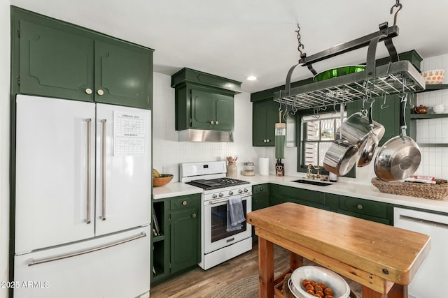 kitchen featuring a sink, white appliances, under cabinet range hood, and green cabinetry