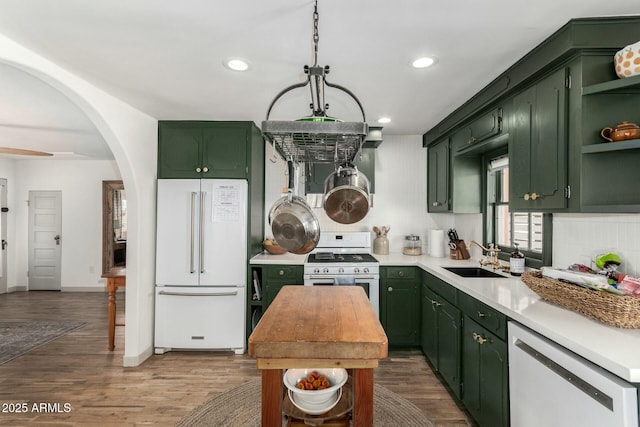 kitchen featuring white appliances, green cabinetry, backsplash, light countertops, and a sink