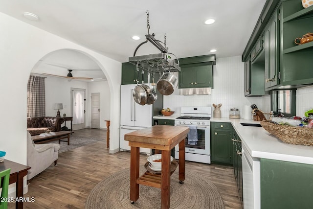 kitchen with light countertops, decorative backsplash, green cabinets, a sink, and white appliances