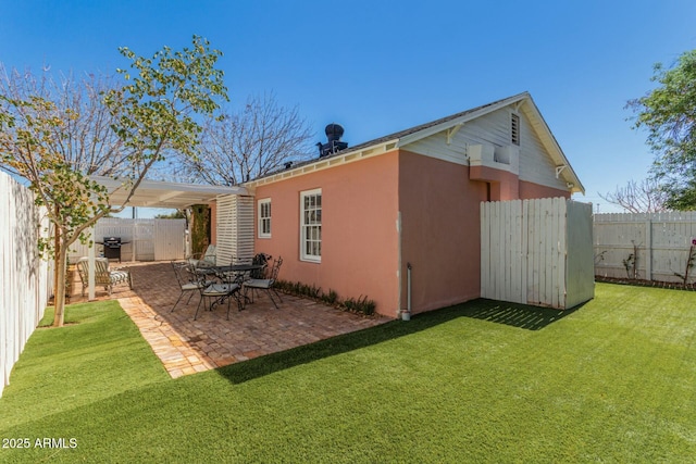 rear view of house with a yard, a fenced backyard, stucco siding, and a patio