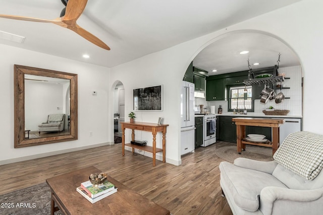 living area featuring arched walkways, visible vents, light wood-style flooring, and a ceiling fan