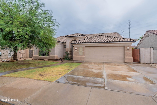 mediterranean / spanish house featuring driveway, a garage, stucco siding, and a tiled roof