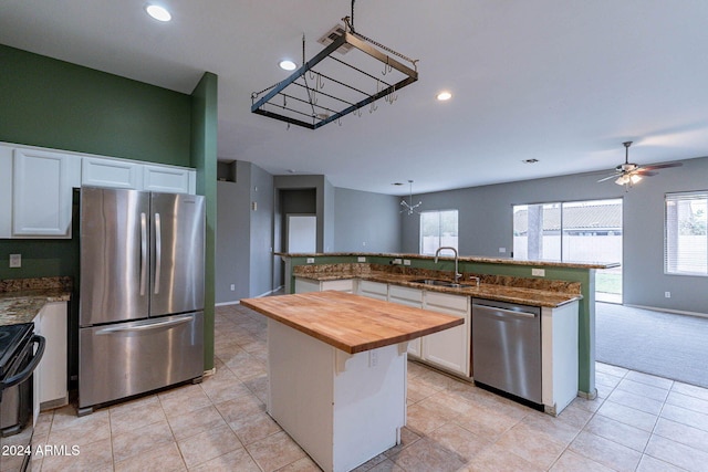 kitchen with a sink, appliances with stainless steel finishes, butcher block counters, recessed lighting, and a center island with sink