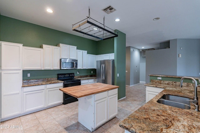 kitchen featuring sink, light stone countertops, a center island, white cabinetry, and appliances with stainless steel finishes