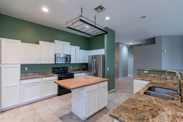 kitchen featuring a sink, stainless steel appliances, visible vents, white cabinetry, and wooden counters