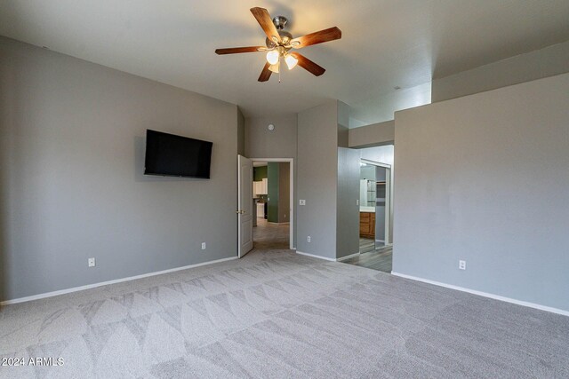 interior space with ensuite bathroom, ceiling fan, light colored carpet, and baseboards