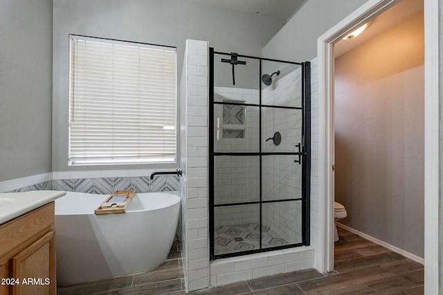 full bath featuring toilet, wood finished floors, a shower stall, and a soaking tub