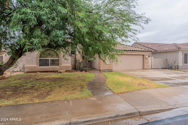 view of front of property with stucco siding, a tiled roof, driveway, and a garage